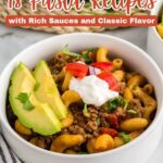 A bowl of pasta with ground meat, tomato, avocado slices, sour cream, and herbs, next to a black-and-white striped cloth. Text reads: 18 Pasta Recipes with Rich Sauces and Classic Flavor.