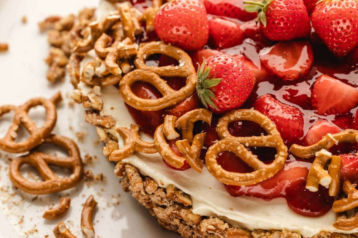 Close-up of a strawberry pretzel tart with a creamy filling and pretzel decorations.