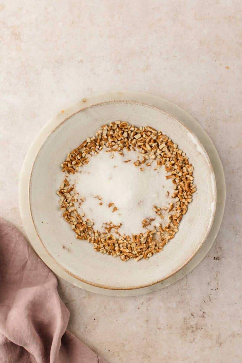 A bowl of sugar with chopped pretzels around the edge.