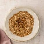 Crushed pretzels in a bowl with liquid and spices.