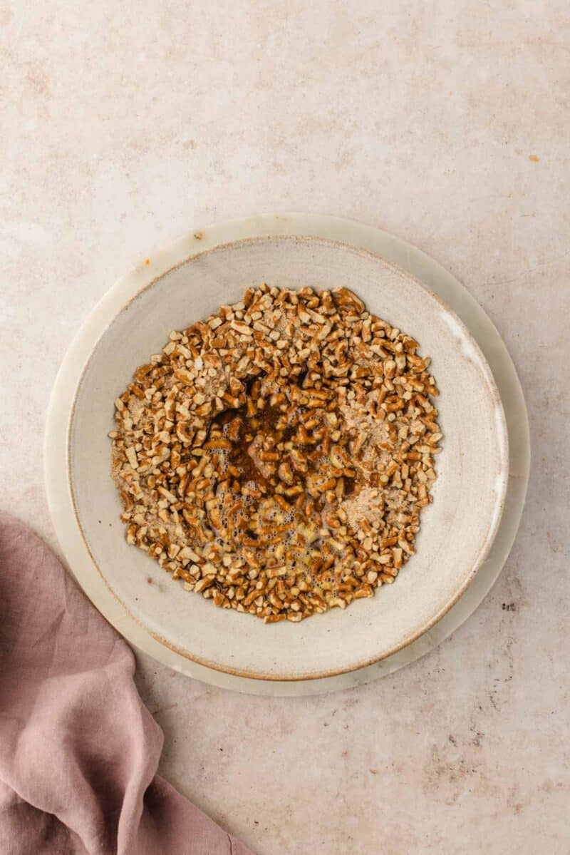 Crushed pretzels in a bowl with liquid and spices.