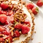 Strawberry pretzel tart with a nutty crust and cream cheese filling, topped with fresh strawberries and pretzel pieces.