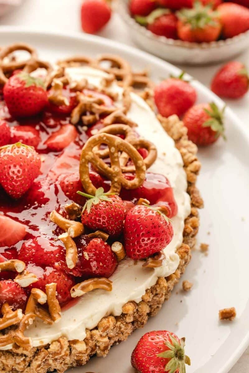 Strawberry pretzel tart with a nutty crust and cream cheese filling, topped with fresh strawberries and pretzel pieces.