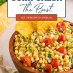 A wooden bowl filled with corn salsa, cherry tomatoes, herbs, and tortilla chips, with text promoting a corn salsa recipe on a blog.