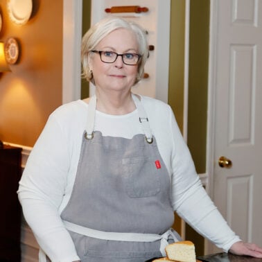 Lana Stuart, of Lanascooking.com, standing in her kitchen in a grey apron.