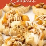 Peach cobbler cookies topped with peach filling, crumbly streusel, and white icing, arranged closely on a light background. Text above reads “Peach Cobbler Cookies.”.