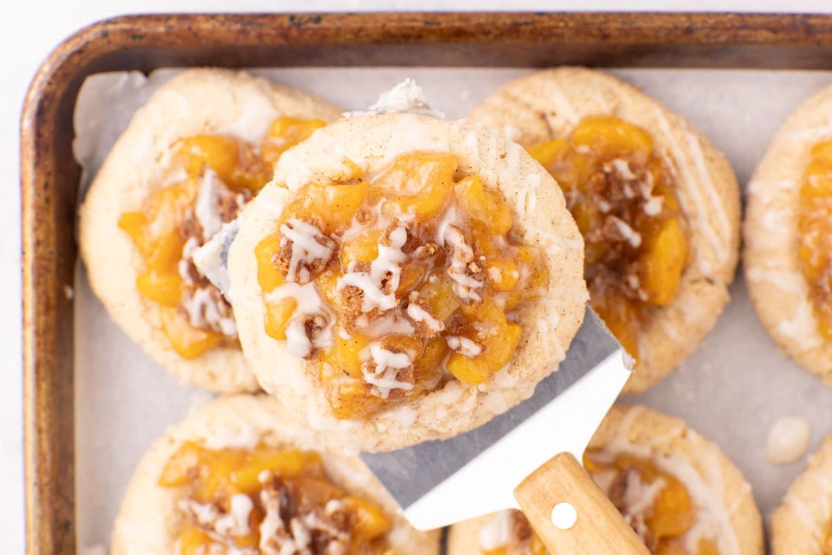 Soft cinnamon cookies with peach cobbler filling, crumble, and vanilla glaze.