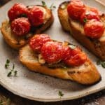 Three slices of toasted bread topped with tomato confit are arranged on a ceramic plate.