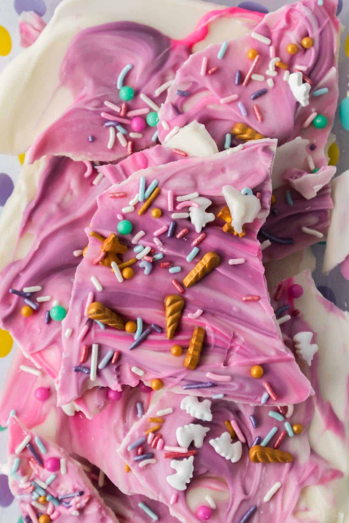 Unicorn bark topped with colorful sprinkles and candy shapes, broken into uneven pieces.
