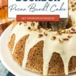 A pecan bundt cake with white icing and chopped pecans sits on a plate next to a glass of bourbon. Text overlay reads “Bourbon Pecan Bundt Cake.”.