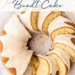 Iced cinnamon roll bundt cake with several slices cut, displayed on parchment paper. Text overlay reads “Cinnamon Roll Bundt Cake.”.