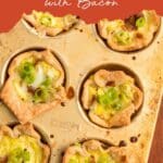 A muffin pan with six mini quiches topped with chopped green onions and pieces of bacon, set on a brown background.