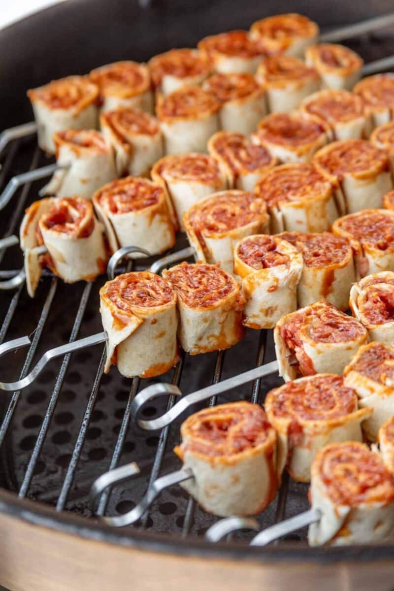 Close-up of bbq tortilla roll ups, skewered and grilling on a barbecue grate.