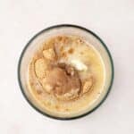A glass bowl containing melted butter, brown sugar, and graham cracker crumbs on a light surface.