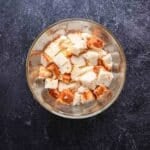A clear bowl filled with cubed pieces of bread sits on a dark textured surface.