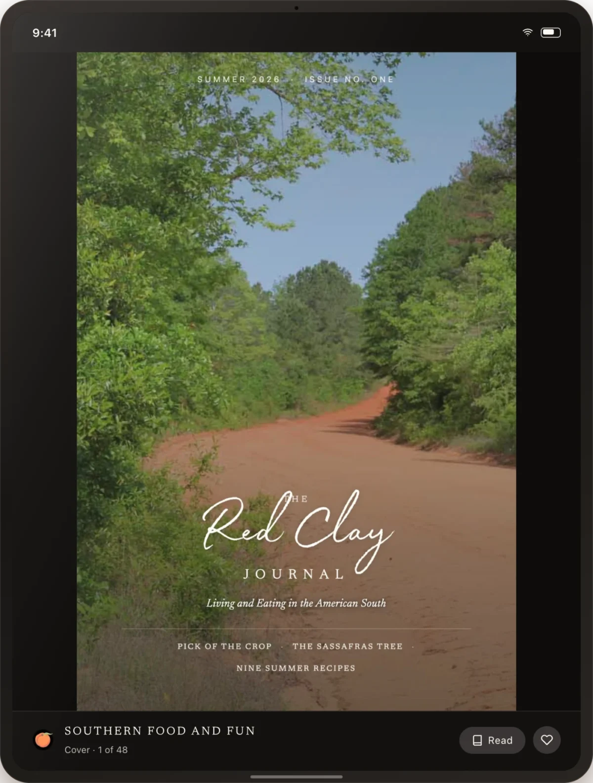 A rural red clay road bordered by green trees under a blue sky, featured on the cover of The Red Clay Journal magazine displayed on a tablet screen.