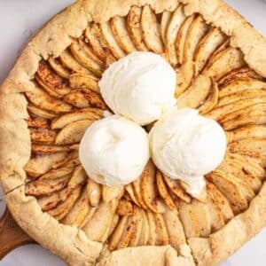 An apple galette topped with three scoops of vanilla ice cream.