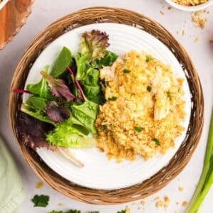 A plate of casserole topped with breadcrumbs, served with a side of mixed greens.