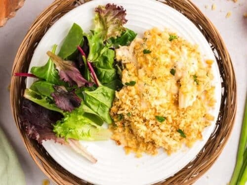 A plate of casserole topped with breadcrumbs, served with a side of mixed greens.
