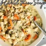 A bowl of creamy chicken and wild rice soup with carrots, celery, and herbs.