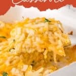 A serving of cheesy hash brown casserole being lifted from a baking dish with a spatula.