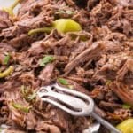Slow cooker Mississippi pot roast with pepperoncini peppers and a serving fork.