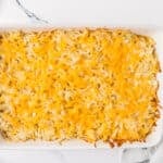 A rectangular baking dish filled with shredded hash brown casserole topped with melted cheddar cheese.