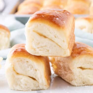 A stack of three golden-brown dinner rolls with a small bowl of butter.