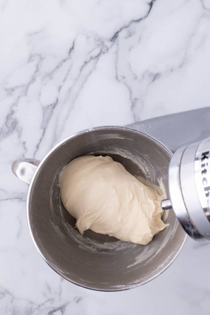 Dough in the metal bowl of a stand mixer.