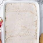 A rectangular baking dish filled with a layer of dry flour or cake mix, accompanied by small bowls of melted butter and crumbled topping.