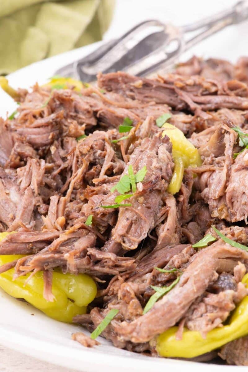 Shredded mississippi pot roast with yellow pepperoncini peppers and fresh herbs.