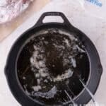 Hot butter bubbling in a cast iron skillet, with a raw roast and butter sticks nearby.